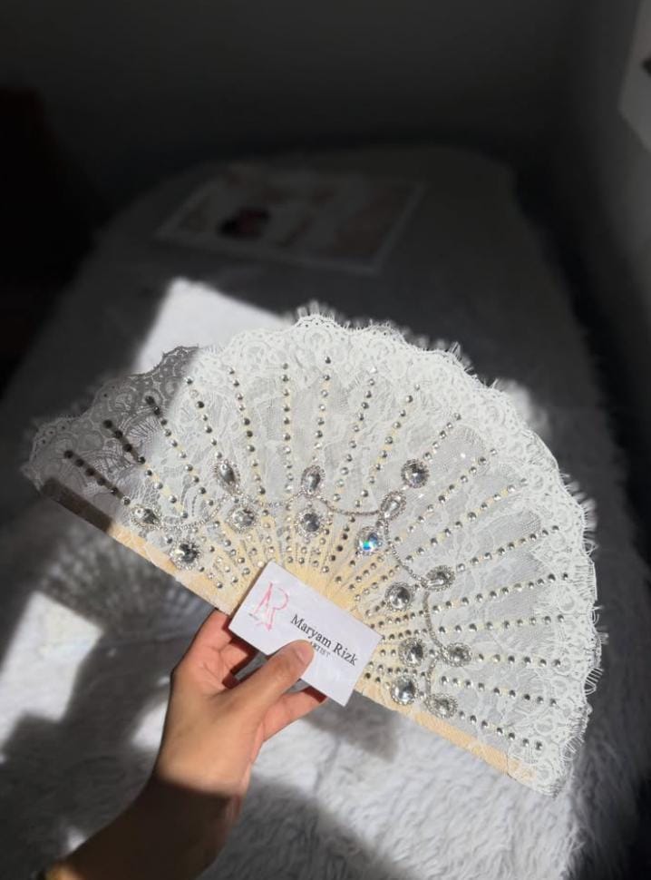 White beaded bridal fan in sunlight